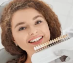 woman-smiling-while-male-dentist-keeping-teeth-color-range